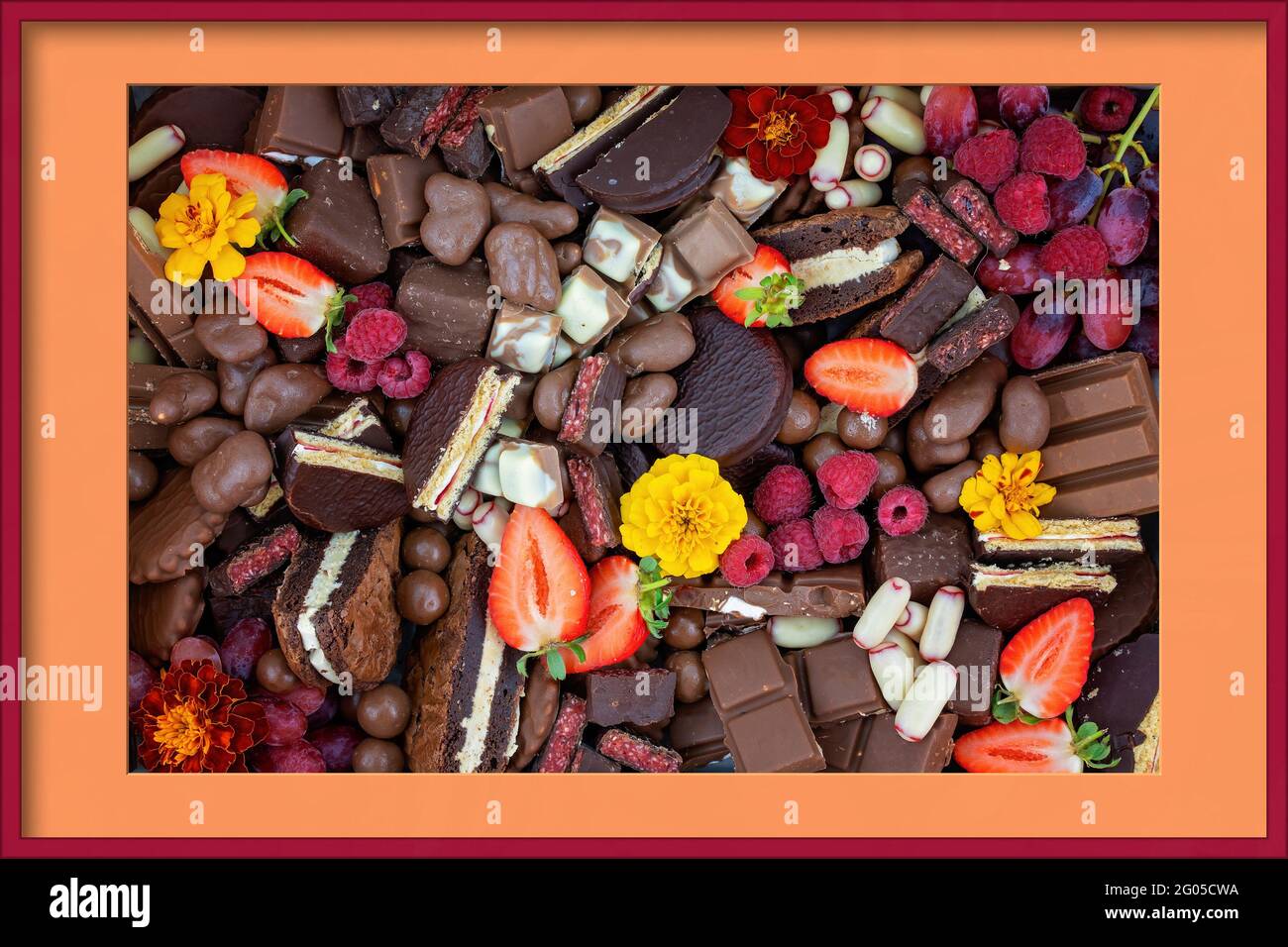 Schokoladendessert-Sortiment mit Obst und Blumen als dekadente Verwöhnteller, präsentiert in einem Fotorahmen Stockfoto