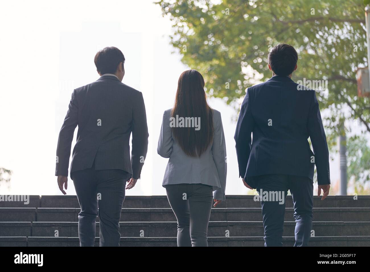 Rückansicht von drei jungen erfolgreichen asiatischen Geschäftsleuten, die aufsteigen Schritte Stockfoto
