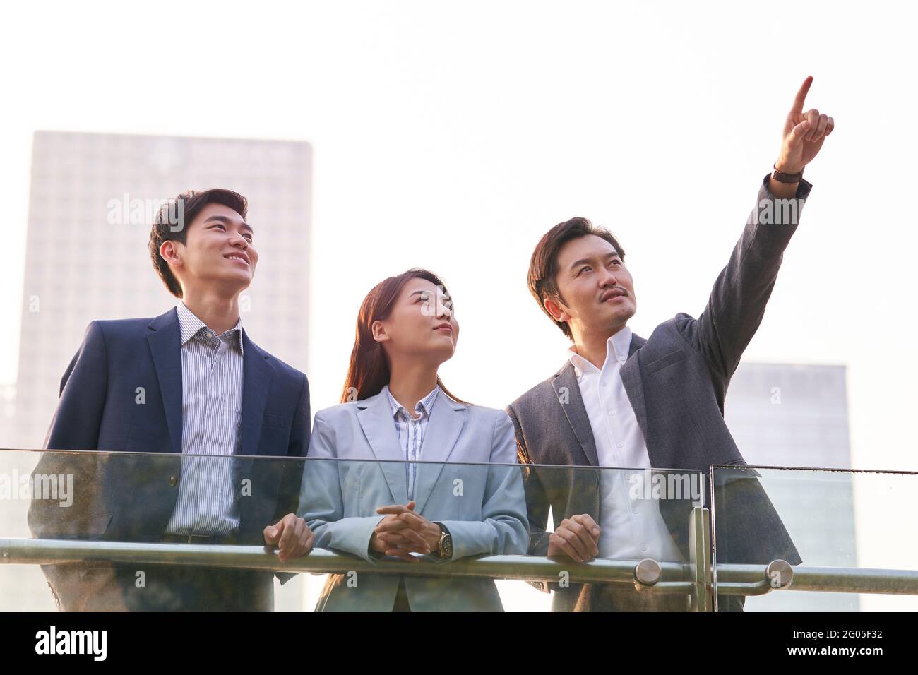 Drei glückliche asiatische Geschäftsleute unterhalten sich im Gespräch über Geschäfte im Freien Stockfoto