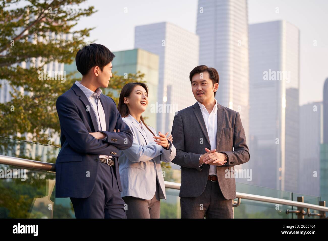 Drei glückliche asiatische Geschäftsleute unterhalten sich im Gespräch über Geschäfte im Freien Stockfoto