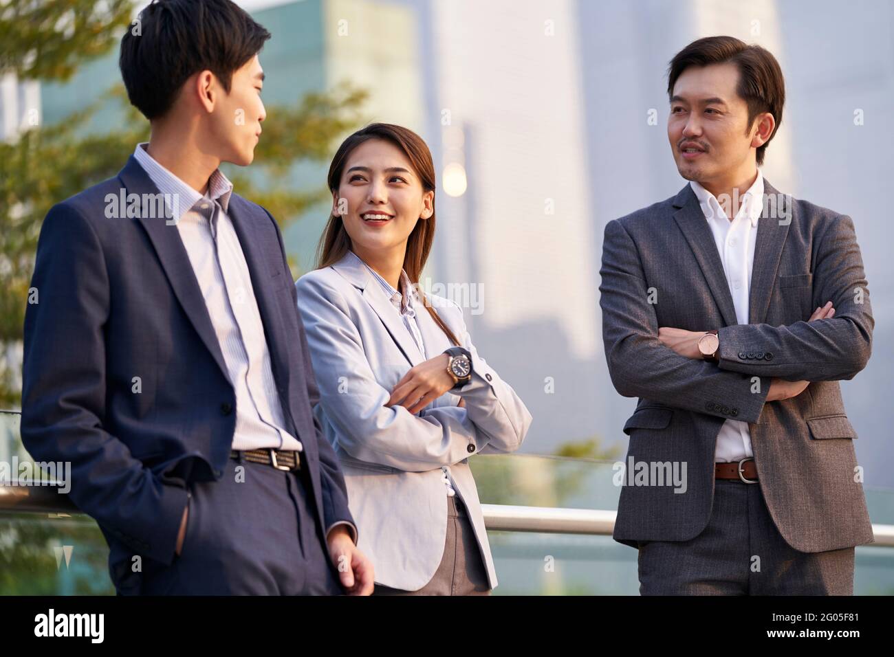 Drei glückliche asiatische Geschäftsleute unterhalten sich im Gespräch über Geschäfte im Freien Stockfoto