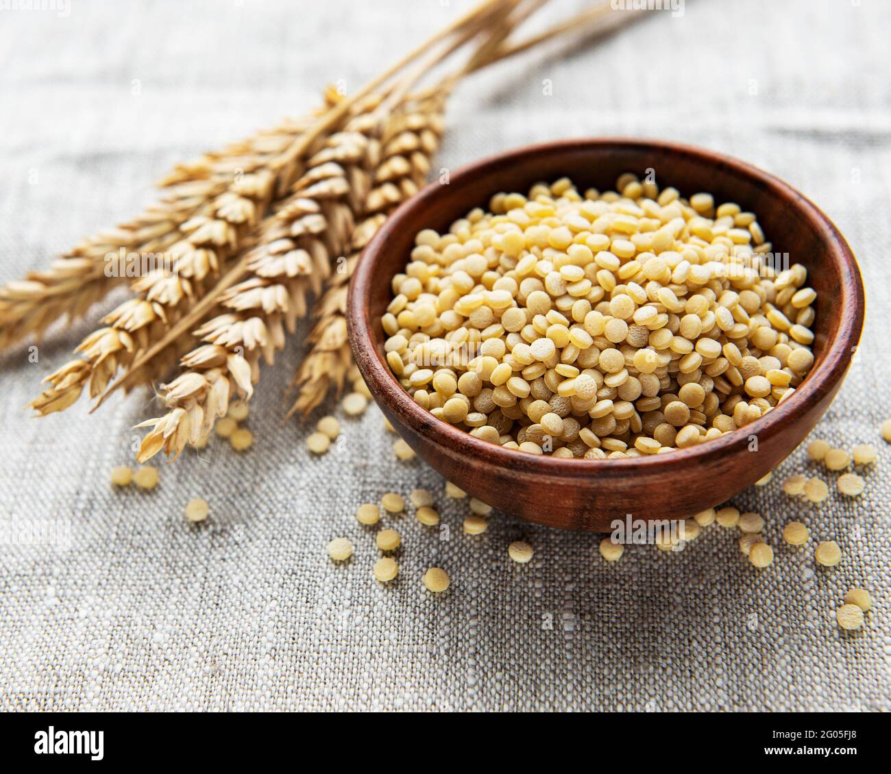 Roher Couscous in einer Holzschale auf dem Tisch Stockfoto