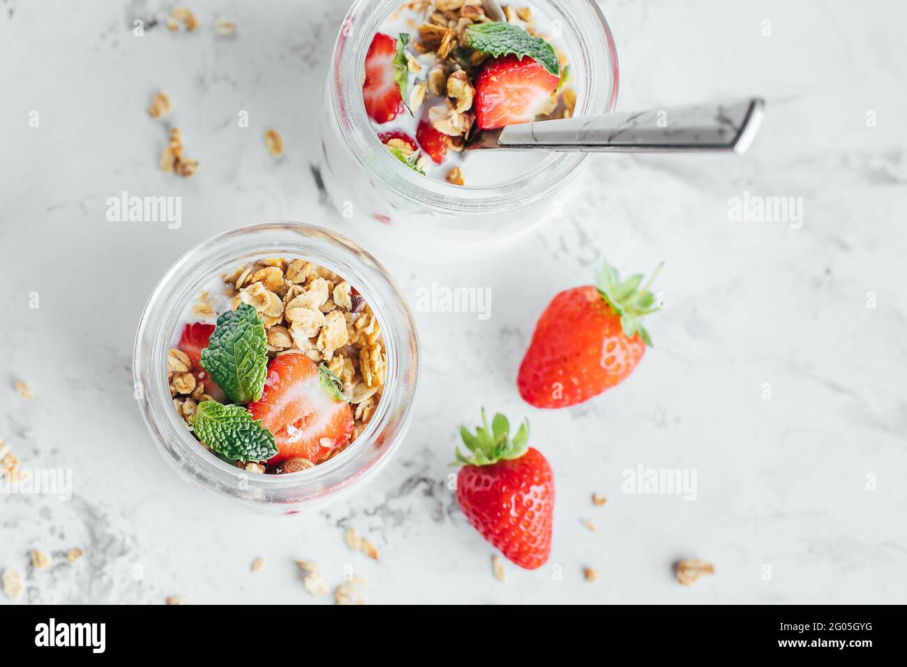 Das Frühstück war lecker. Gläser mit Parfaits aus Müsli, Erdbeeren, Joghurt auf Marmortisch Stockfoto