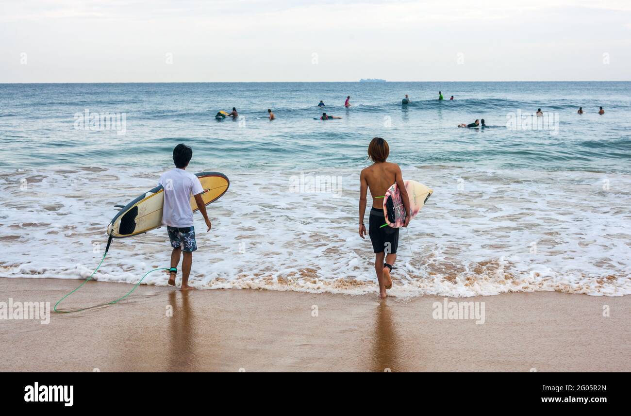 Rückansicht von zwei Surfern mit Surfbrettern, die zum Meer gehen, Hikkaduwa, Südprovinz, Sri lanka Stockfoto