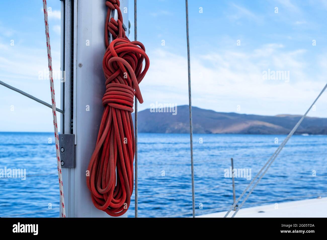 Festmachen Seile auf dem Segelboot, verwischen Seestücke Hintergrund. Rotes Segelseil auf dem Schiffsmast. Nahaufnahme, Platz kopieren. Segelbootkreuzfahrkarte Stockfoto