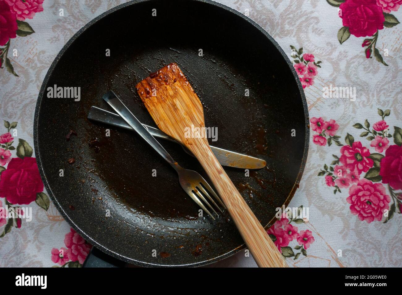 Verschmutzte Gabel und Messer in einer schmutzigen Pfanne Stockfoto