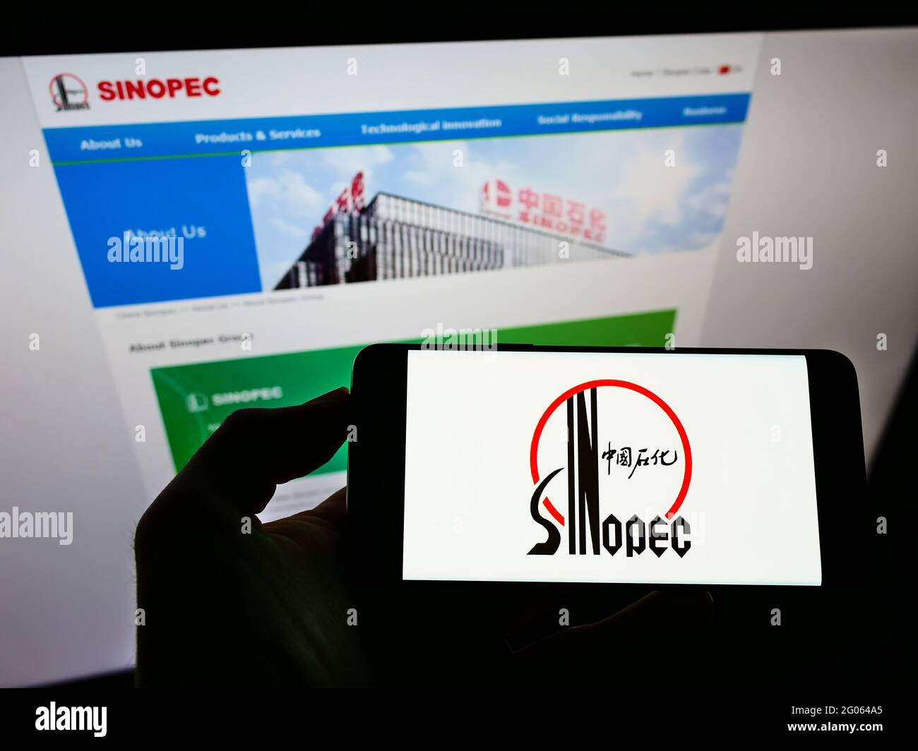 Person, die das Smartphone mit dem Logo der Firma China Petrochemical Corporation (Sinopec) auf dem Bildschirm vor der Website hält. Konzentrieren Sie sich auf die Telefonanzeige. Stockfoto