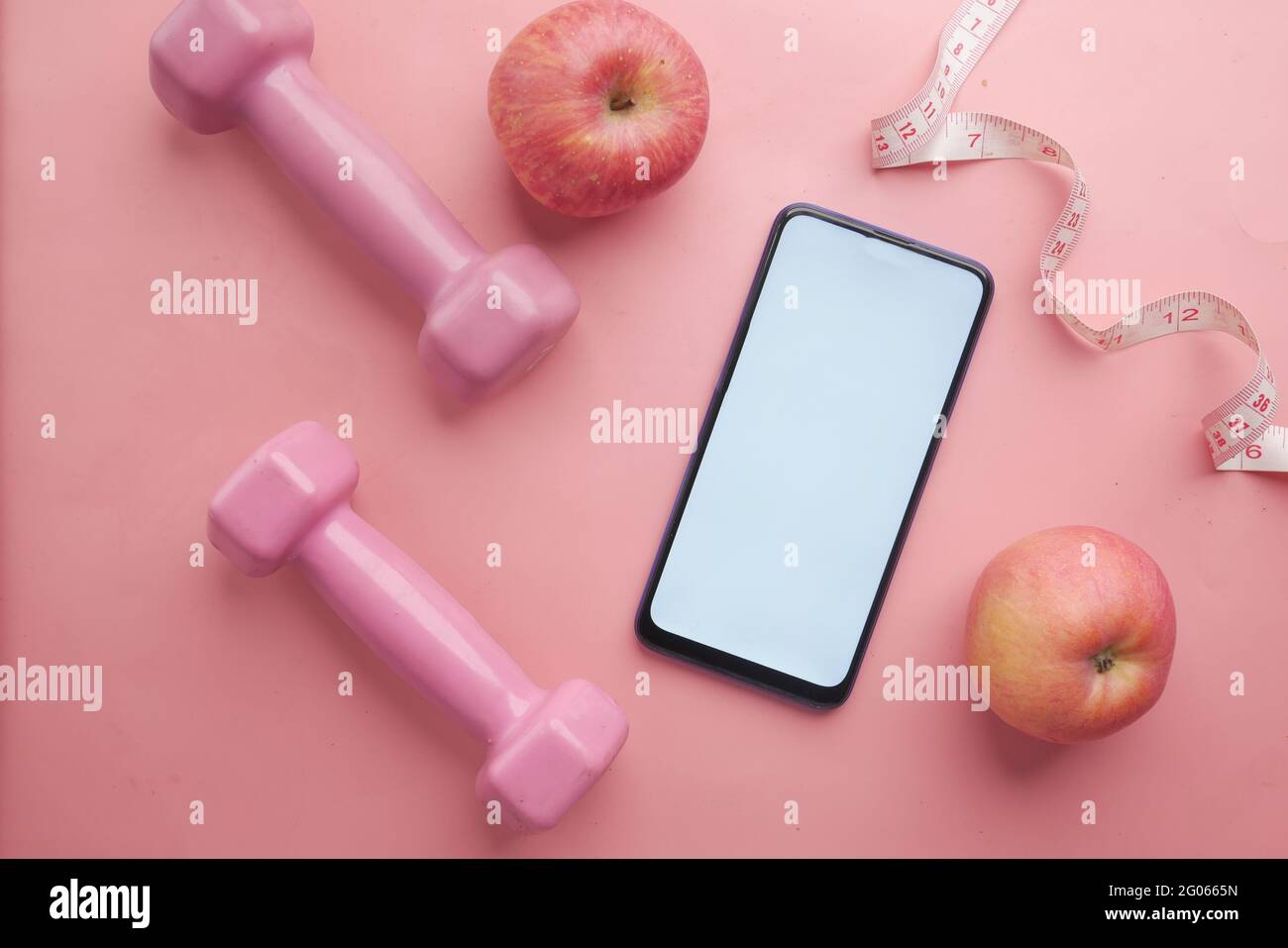 Smartphone mit Sportausrüstung auf rosa Hintergrund Stockfoto