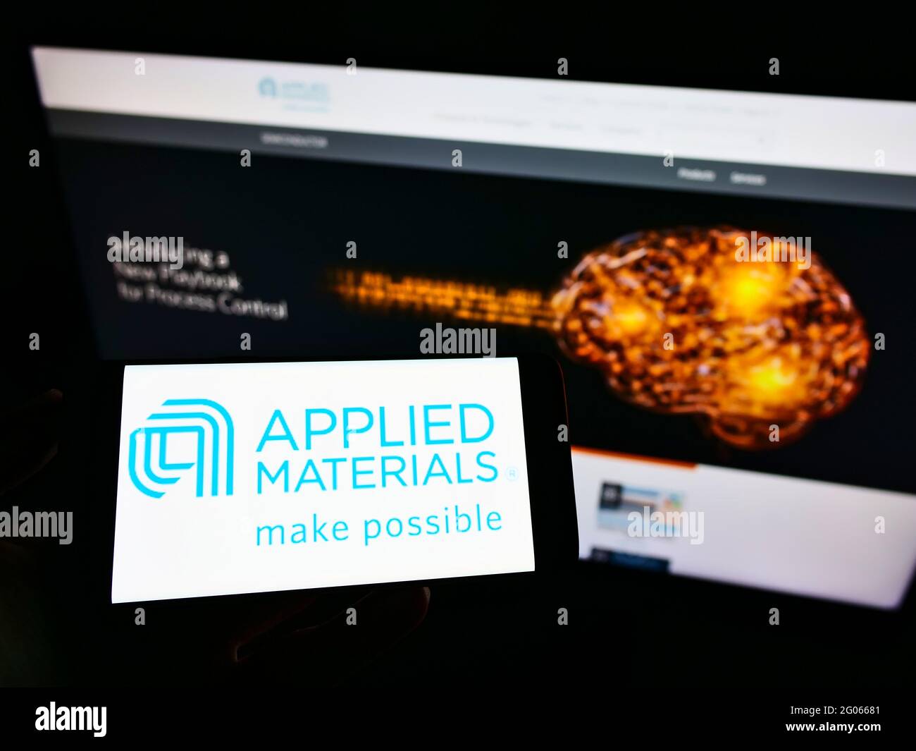 Person mit Mobiltelefon und Logo des amerikanischen Halbleiterunternehmens Applied Materials Inc. Auf dem Bildschirm vor der Webseite. Konzentrieren Sie sich auf die Telefonanzeige. Stockfoto