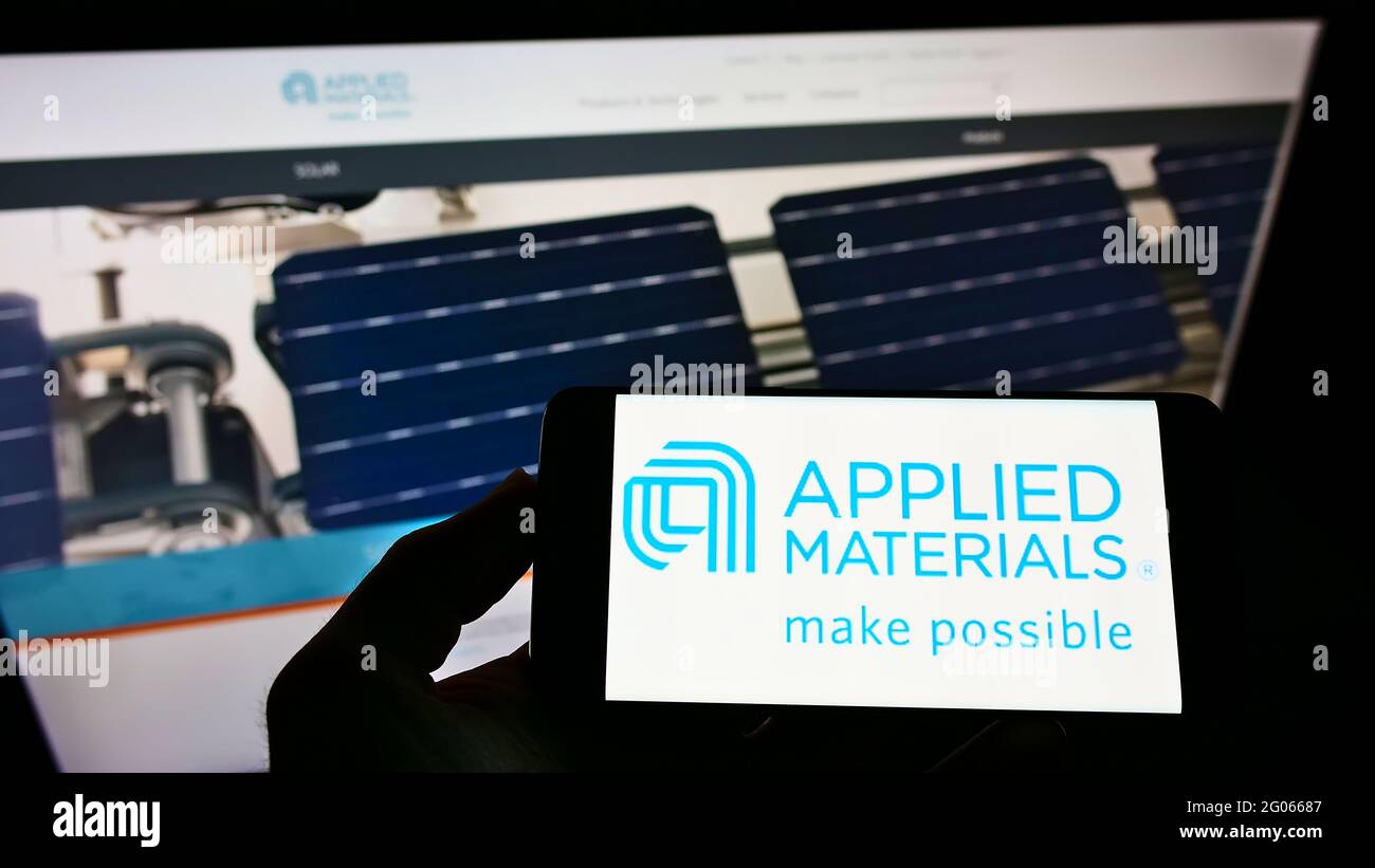 Person mit Mobiltelefon und Logo des US-Halbleiterunternehmens Applied Materials Inc. Auf dem Bildschirm vor der Unternehmenswebsite. Konzentrieren Sie sich auf die Telefonanzeige. Stockfoto