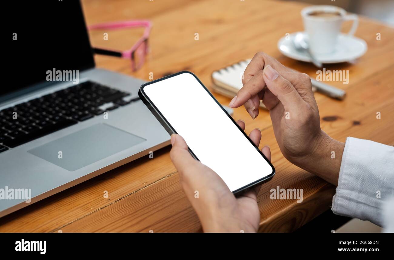 Frau hält und berührt einen leeren mobilen Bildschirm, um sich mit dem Arbeitsbereich im Café zu verspotten Stockfoto