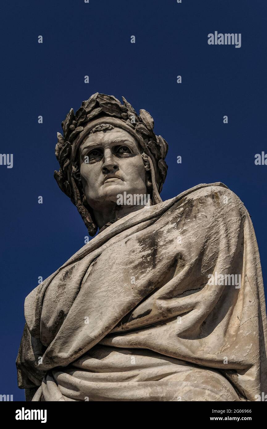 Dante Alighieri (c. 1265-1321), Dichter, Philosoph und Autor der Göttlichen Komödie, starrt in einen klaren blauen Himmel über der Franziskanerkirche Santa Croce aus dem 13. Jahrhundert auf der Piazza Santa Croce in Florenz, Toskana Italien. Das Denkmal, das Enrico Pazzi anlässlich des 600. Geburtstages von Dante in Florenz geschaffen hat, wurde 1865 in der Mitte des Platzes installiert, aber nach den verheerenden Überschwemmungen des Arno im Jahr 1966 an seinen heutigen Standort neben der Kirche verlegt. Stockfoto