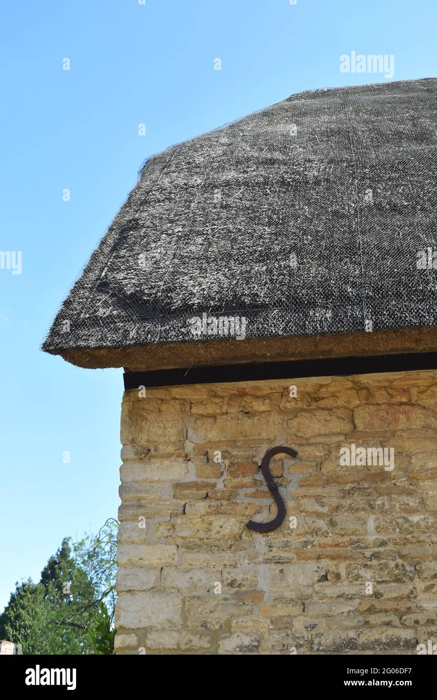 S-förmige Wandbindung an einem Steingebäude mit Reetdach. Stockfoto