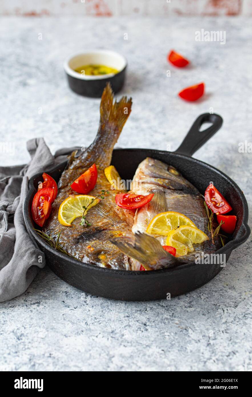 Gegrillter Fisch, Meeresbrasse oder dorado in gusseiserner Pfanne Stockfoto