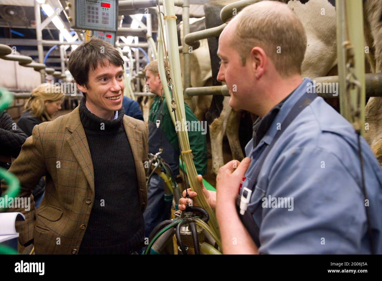 Rory Stewart, der konservative Kandidat des Parlaments für den Penrith und den Wahlkreis der Grenze, sprach mit dem Landwirt Richard Gibson während des Melkens am Morgen. Teil des Wahlkampfs von Rory aus dem Jahr 2010. Castlesteads Farm, Plumpton, Cumbria, Großbritannien. 16 April 2010 Stockfoto