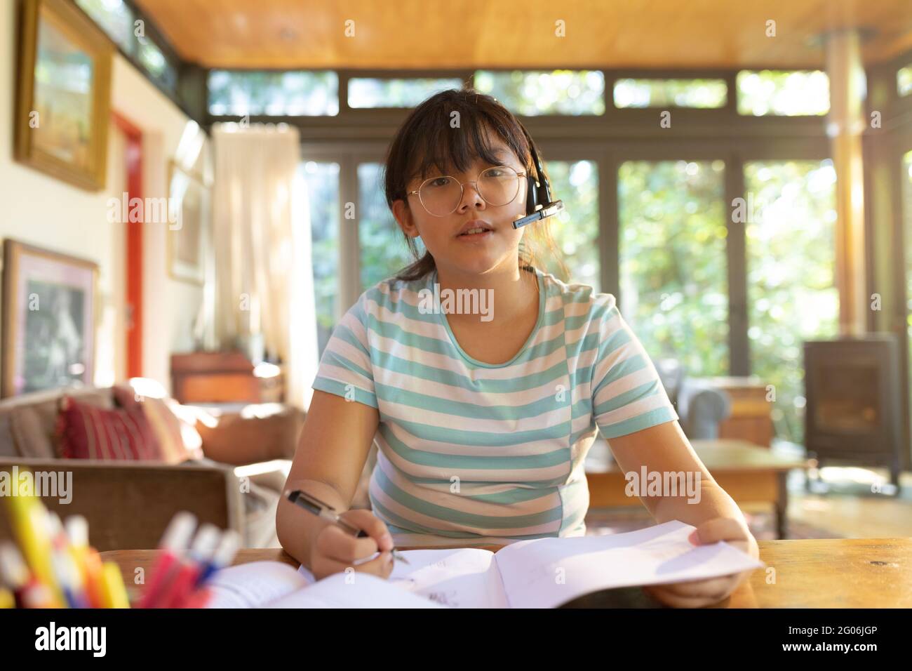 Asiatische Mädchen trägt Telefon-Headset während Videoanruf, online lernen Stockfoto