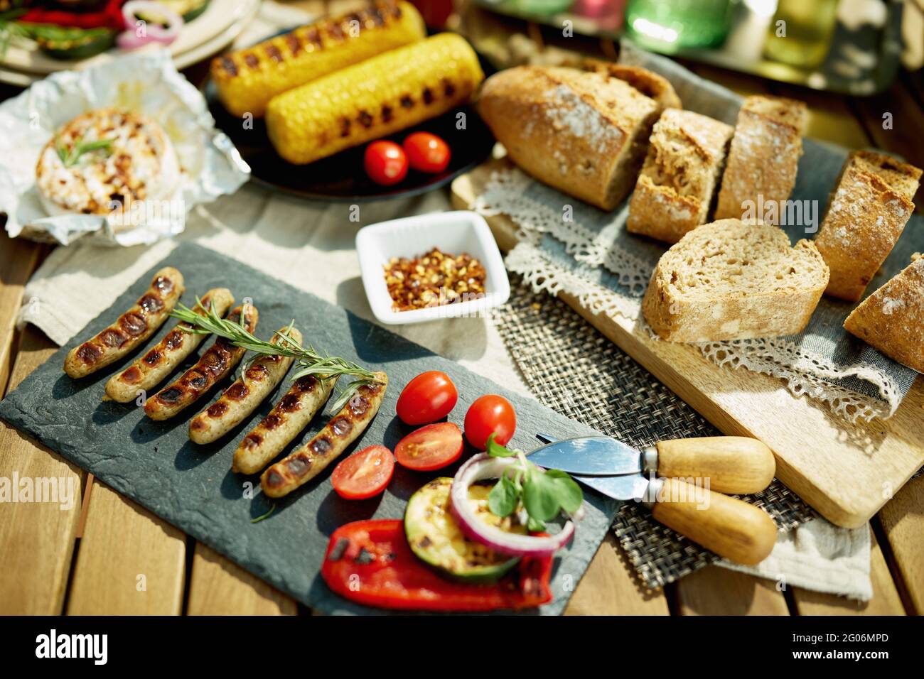 Sommer Hinterhof Party. Schreibtisch mit elektrischem Grill, gegrillte Würstchen, Brot und Camembert. Stockfoto