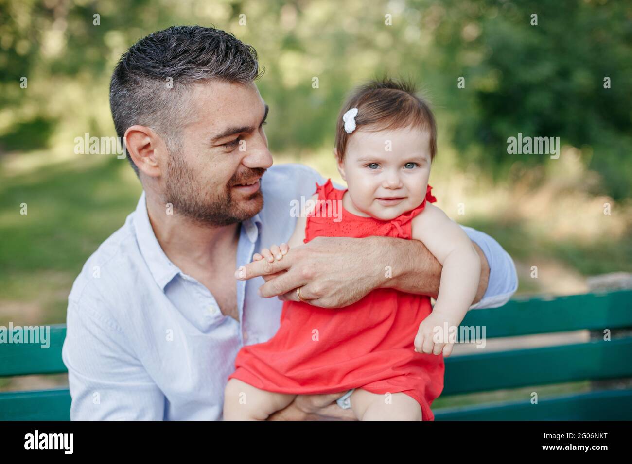Vatertag. Mittelalter kaukasischen stolzen Vater spielt mit Baby Tochter. Familie Vater und Tochter halten Tochter Kleinkind in den Händen im Freien im Park Stockfoto
