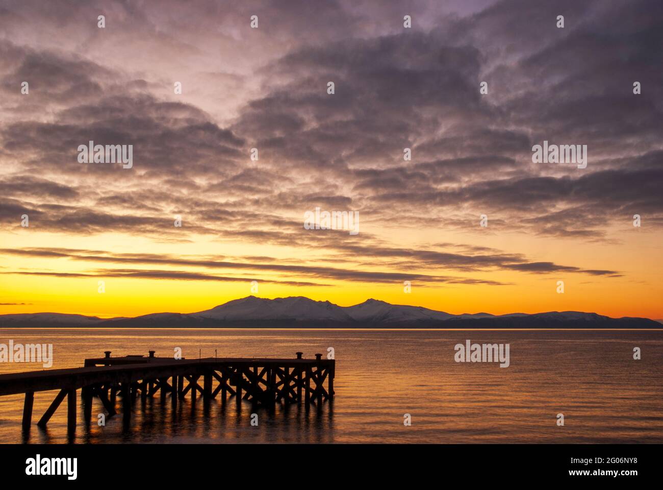 Ein wunderschöner Sonnenuntergang hinter der Isle of Arran, aufgenommen vom alten Pier in Portencross in North Ayrshire, Schottland. Stockfoto