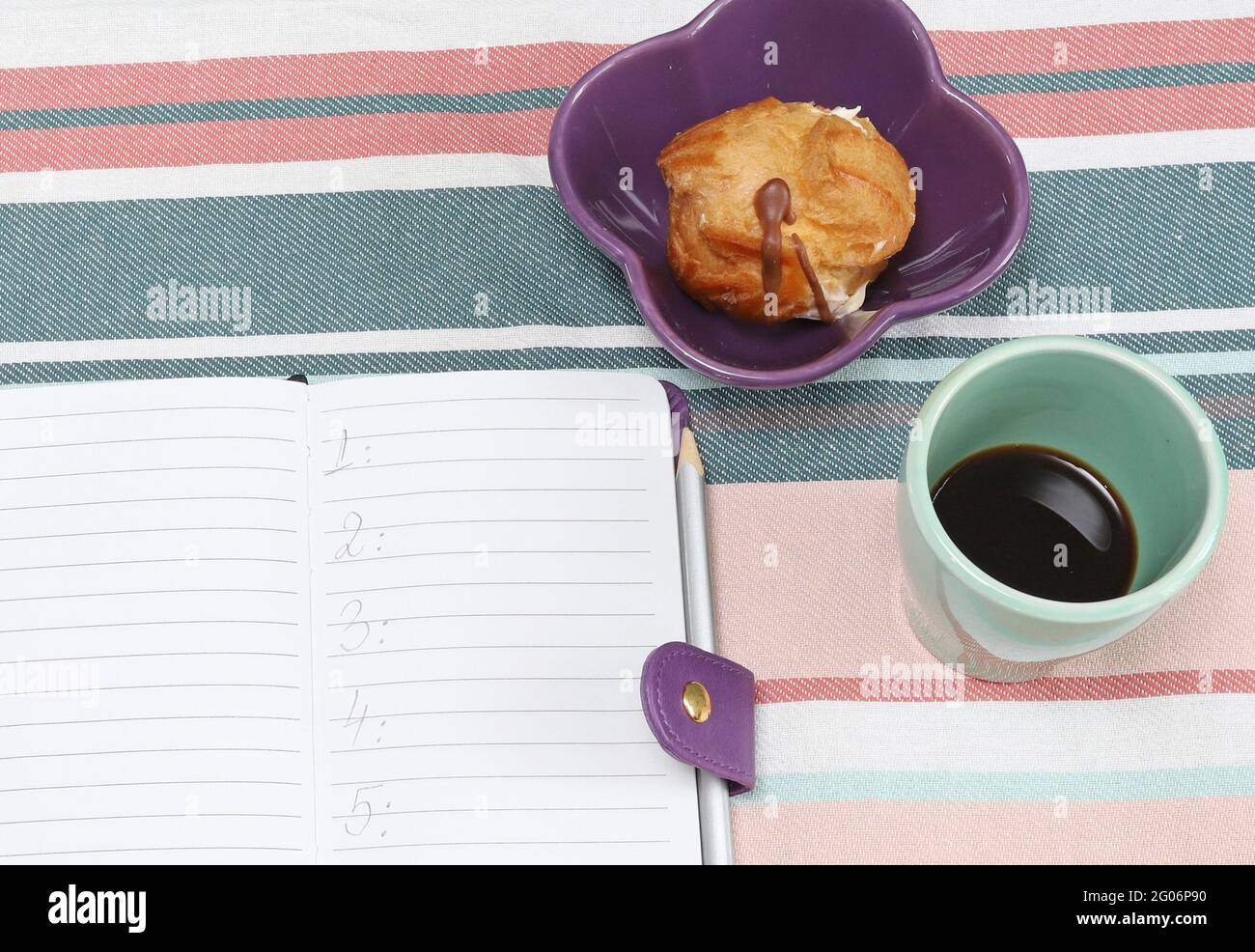 Liste im Notizblock mit Kaffee und Süßigkeiten auf dem Tisch zu tun Stockfoto