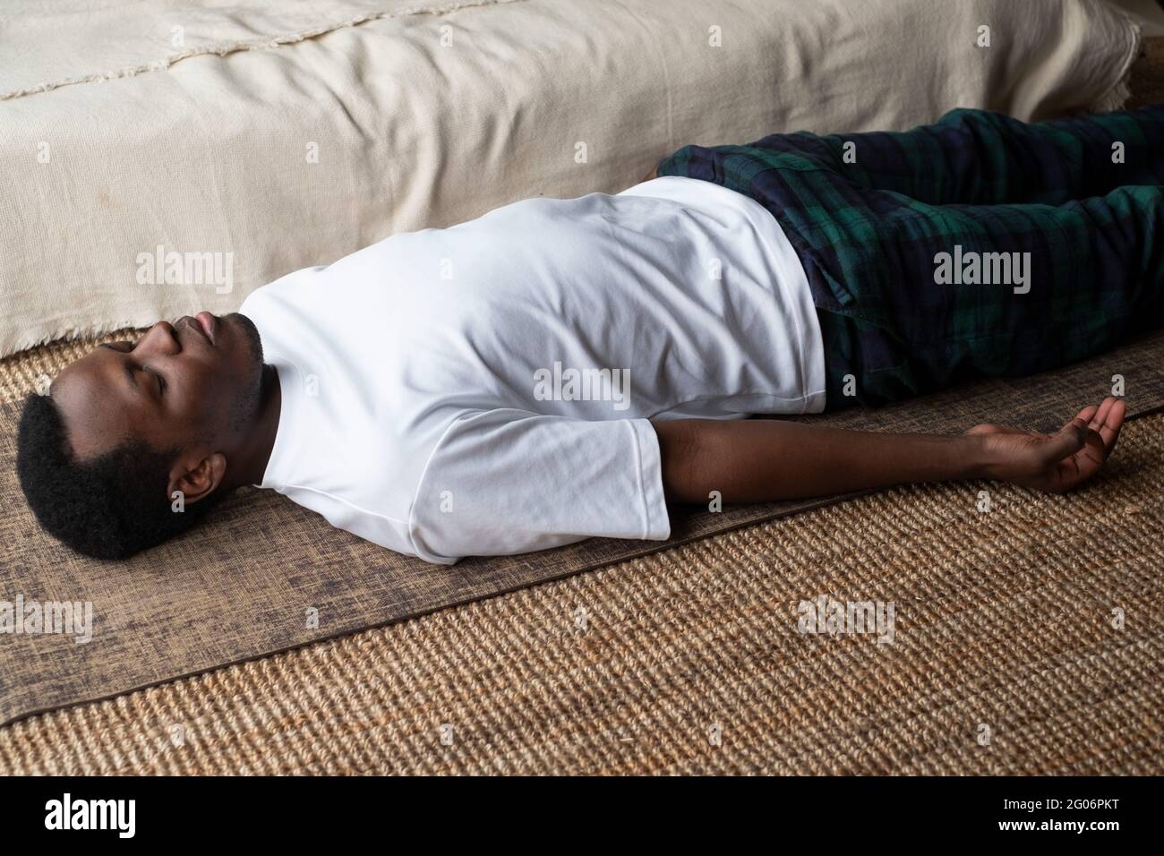 Yoga. Afrikanischer junger Mann, der auf einem Boden meditiert und in Shavasana-Pose liegt. Stockfoto