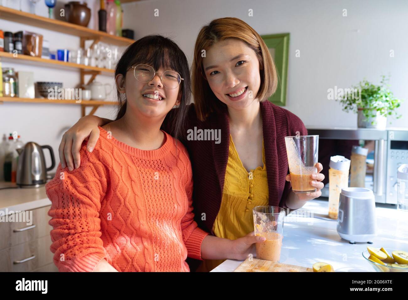 Porträt einer lächelnden asiatischen Mutter und Tochter mit hausgemachtem Smoothie in der Küche Stockfoto