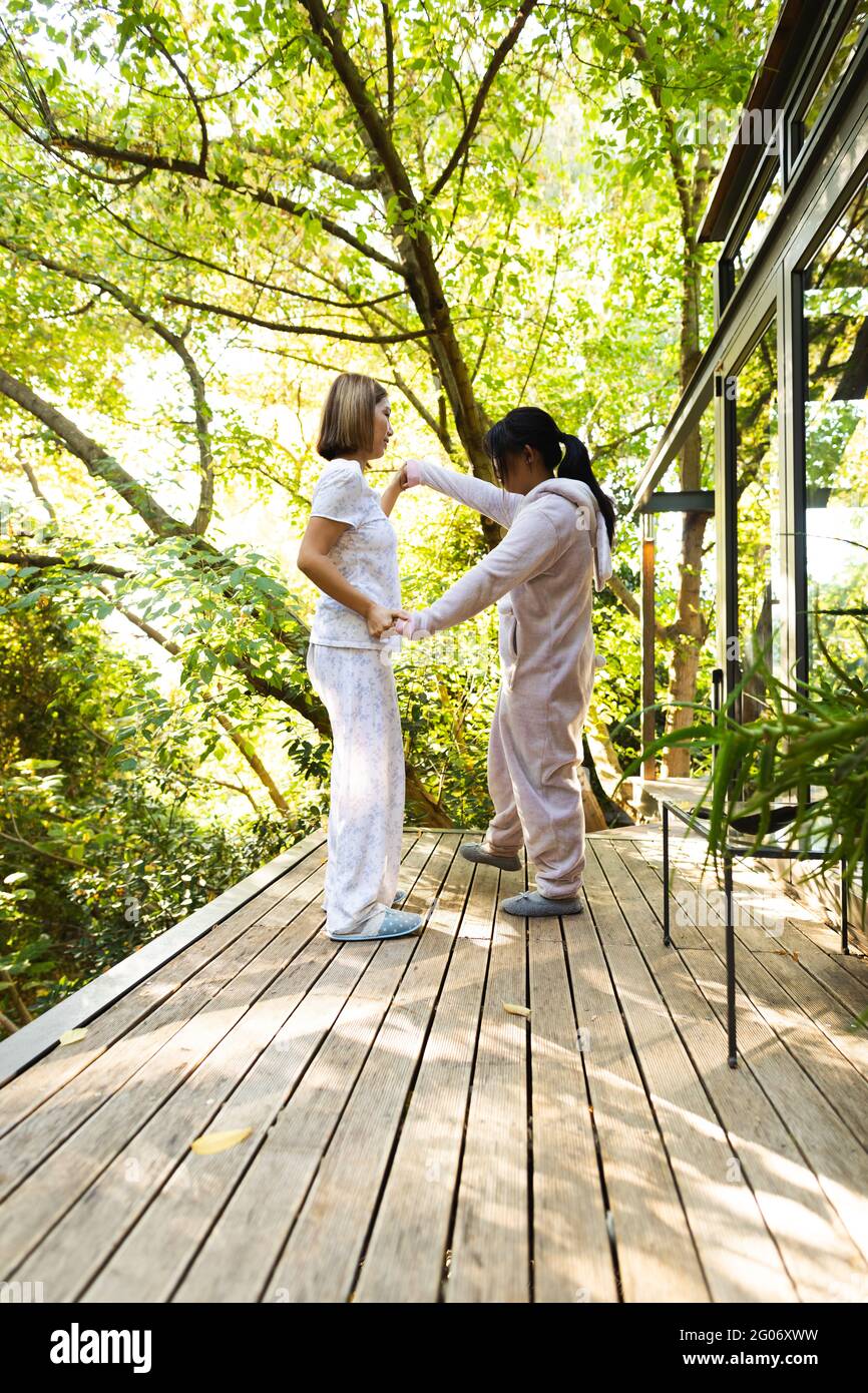 Asiatische Mutter und ihre Tochter tanzen auf der Terrasse im Garten Stockfoto