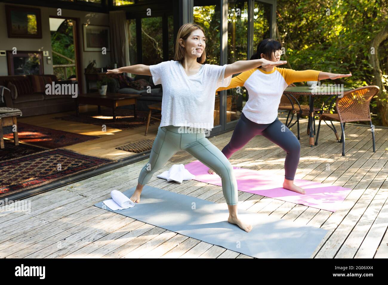 Asiatische Mutter und ihre Tochter üben Yoga auf der Terrasse im Garten Stockfoto