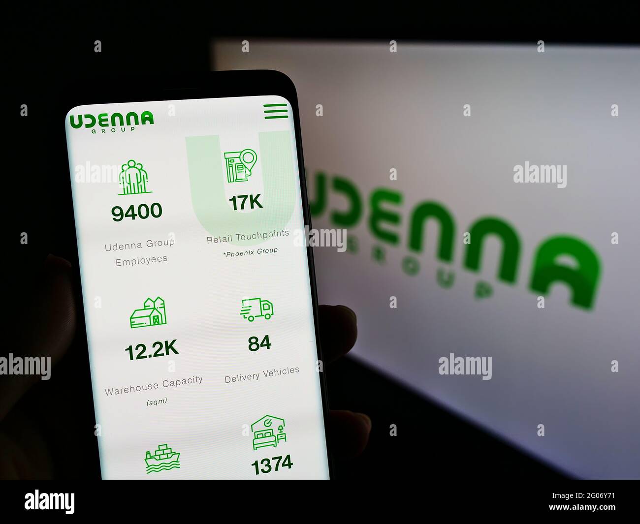 Person, die Smartphone mit Website des philippinischen Konglomerats Udarna Corporation vor dem Logo auf dem Bildschirm hält. Konzentrieren Sie sich auf die Mitte des Telefondisplays. Stockfoto
