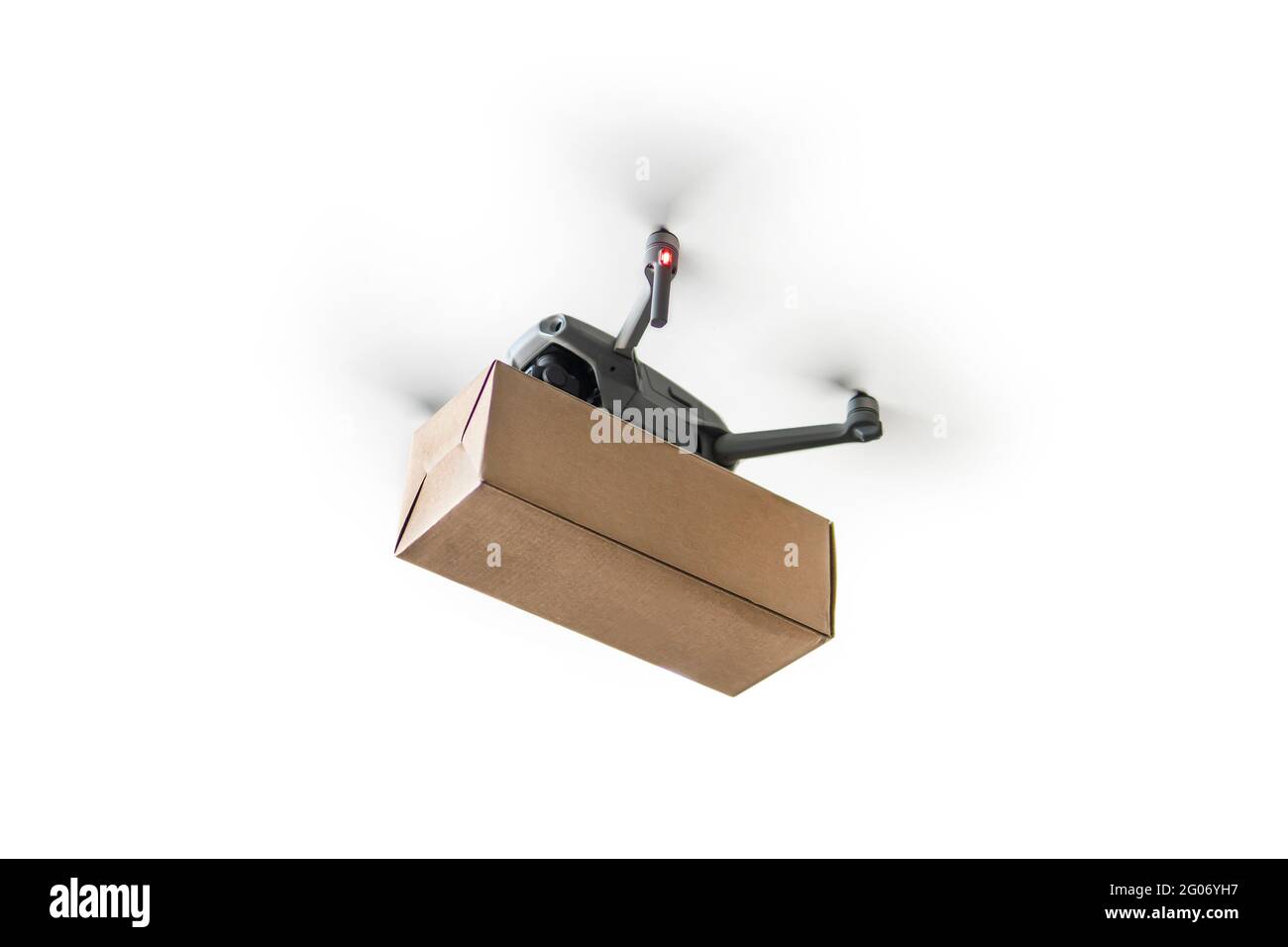 Das Konzept der Luftlieferung von Waren. Luftpost. Der Quadrocopter, der das Paket während des Fluges liefert, ist auf weißem Hintergrund isoliert. Stockfoto