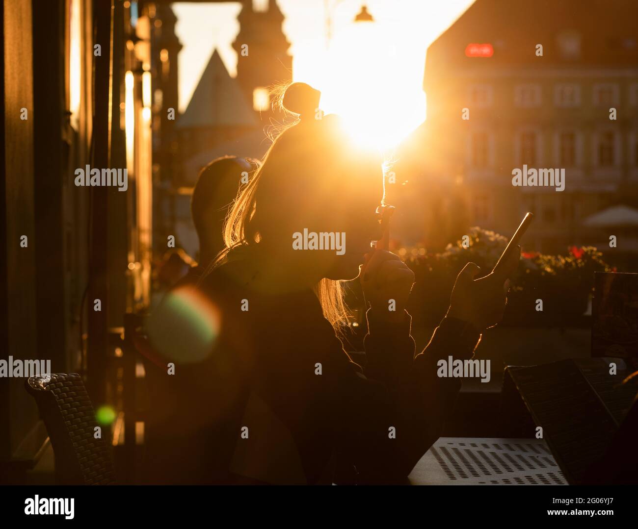 Gniezno, Polen - Silhouetten von Mädchen, die vor dem Hintergrund der untergehenden Sonne an einem Tisch in einer Kneipe sitzen. Stockfoto