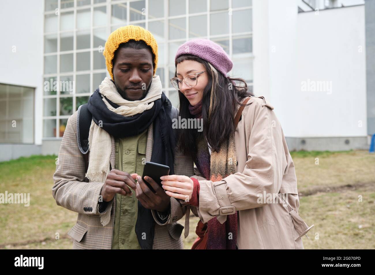 Junges Paar in warmer Kleidung, das im Freien mit einem Mobiltelefon telefoniert Stockfoto