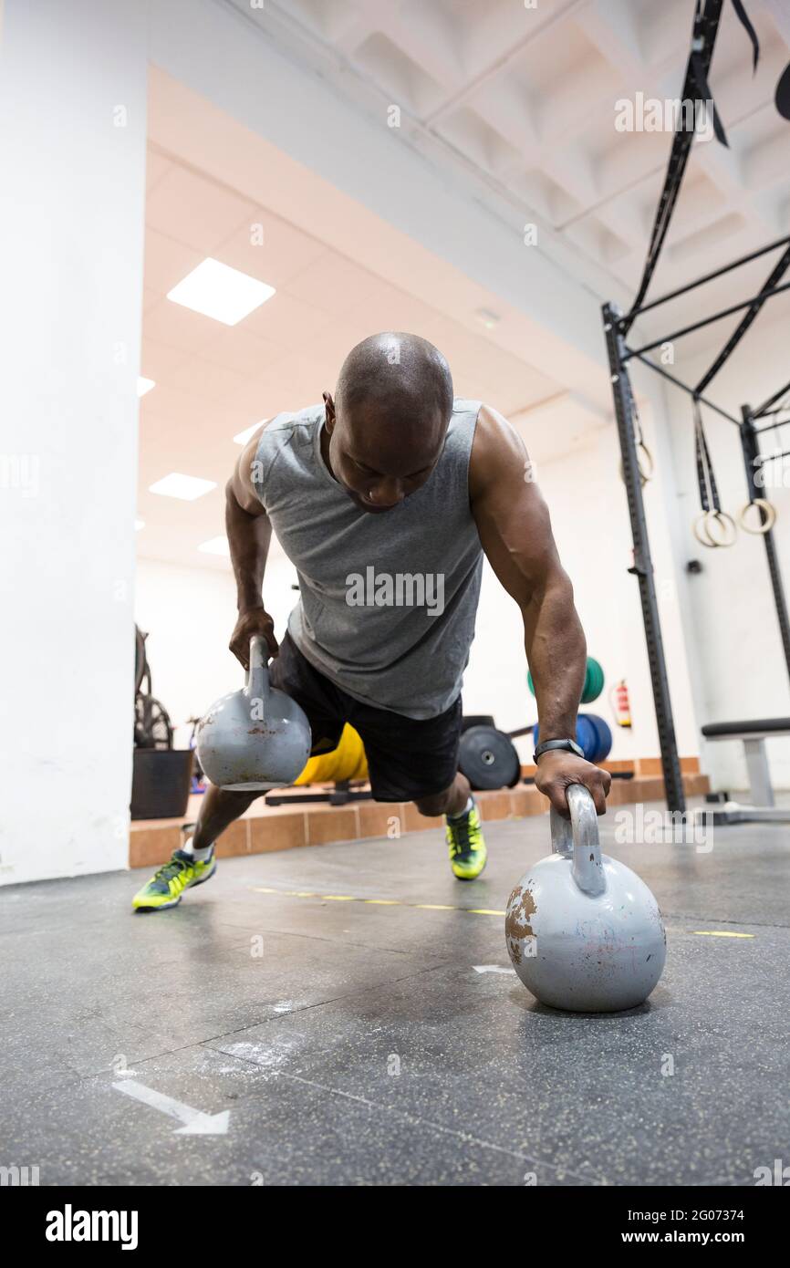 Schwarzer muskulöser Mann, der im Fitnessstudio mit Kettlebells trainiert. Stockfoto