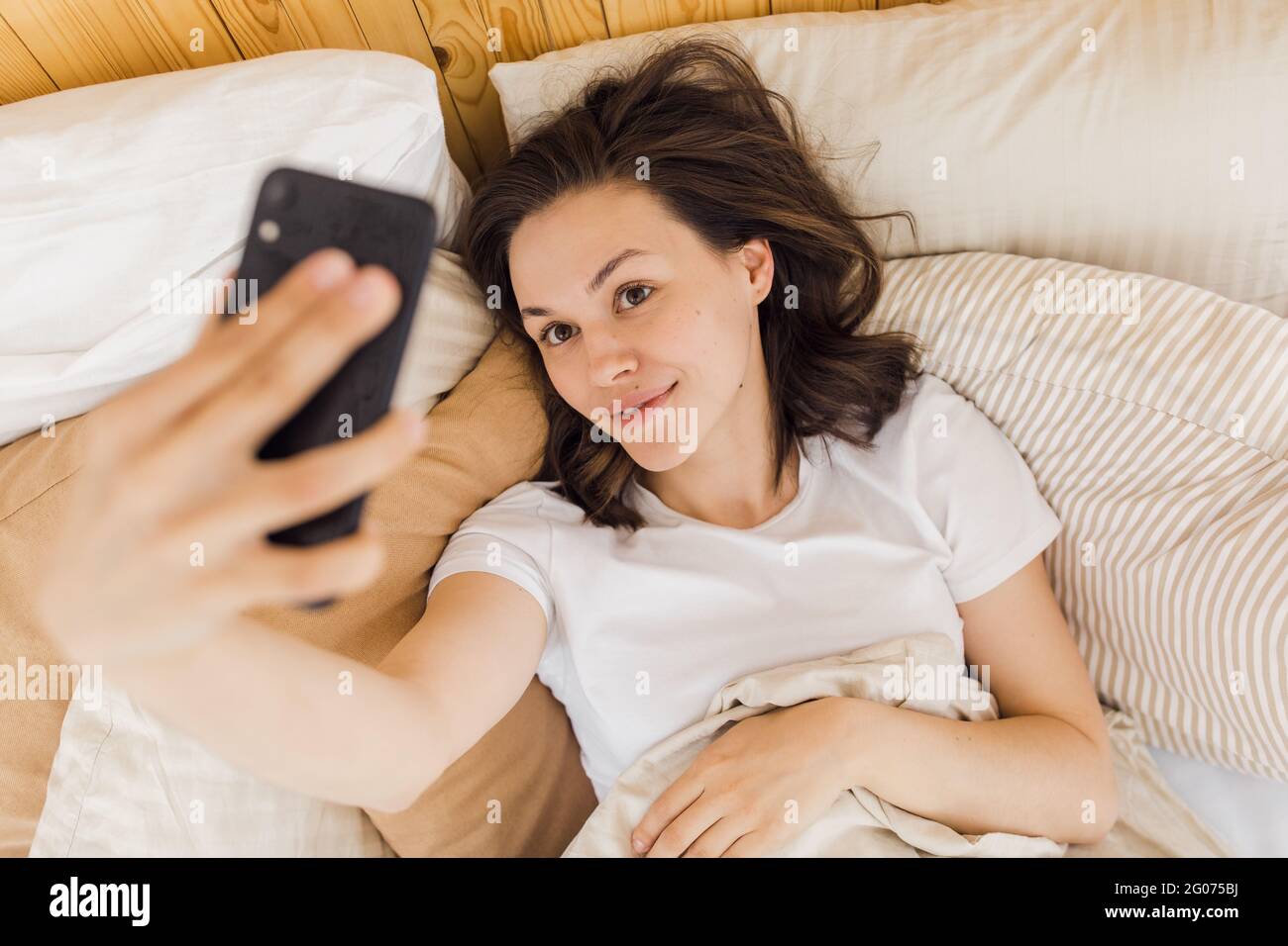 Junge attraktive Frau nimmt ein Selfie kurz nach dem Aufwachen Stockfoto