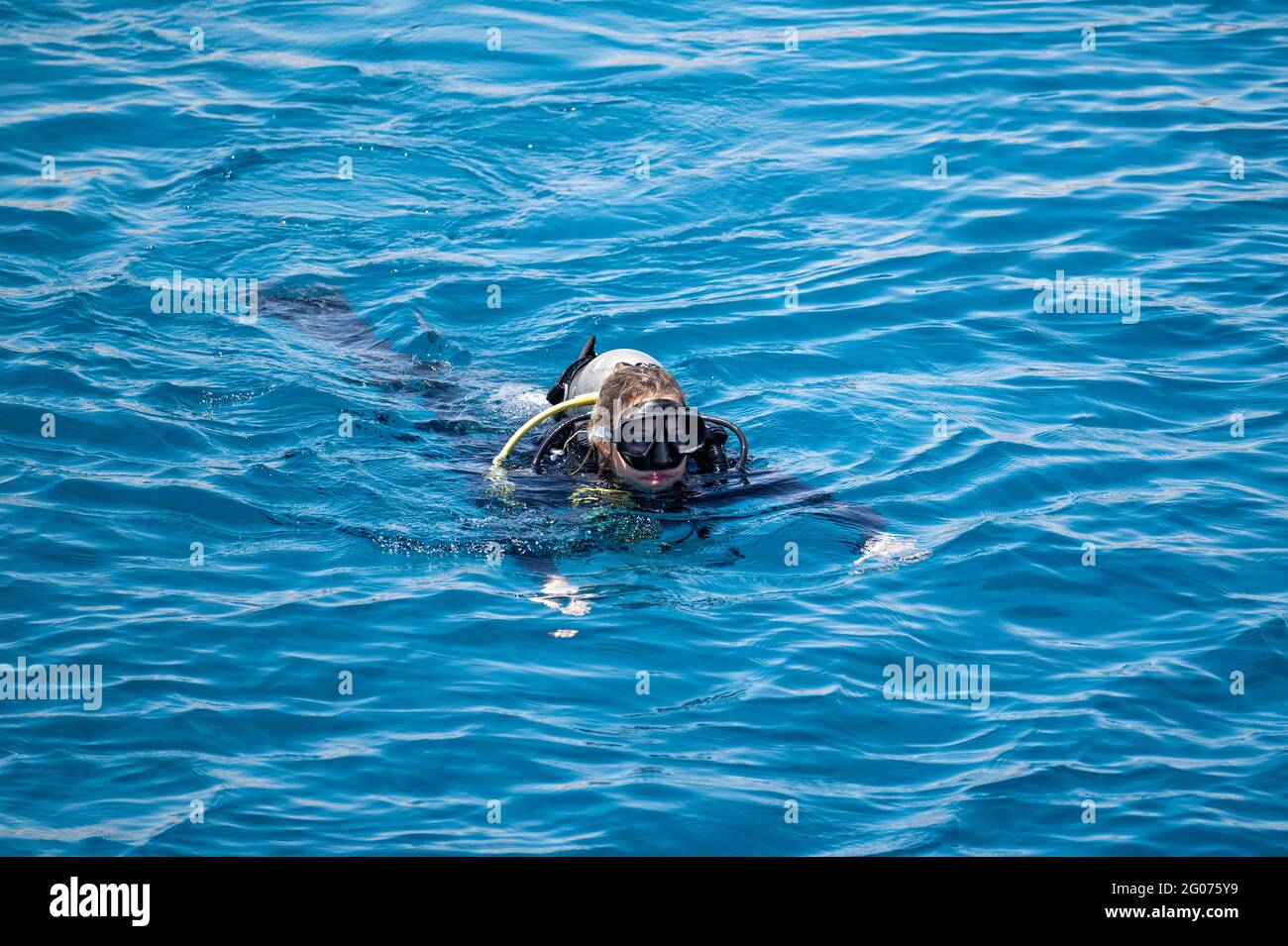 Frau in Scuba schwimmt nach dem Tauchen auf blauer Meeresoberfläche. Wassersport und Unterhaltung, Scuba-Diving-Konzept Stockfoto