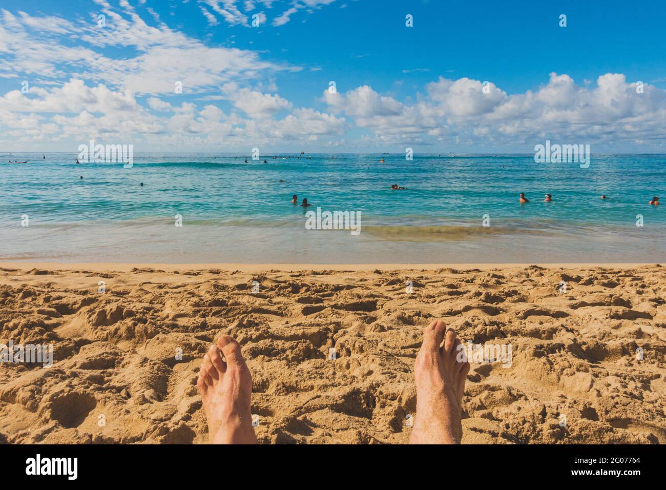 Blick auf die Füße von mans am Sandstrand mit Blick auf den wunderschönen Ozeanhorizont Stockfoto