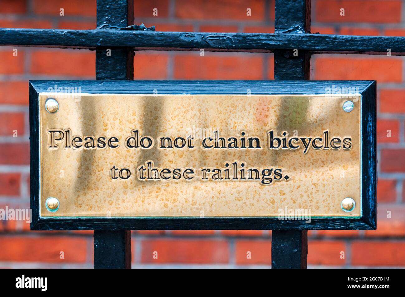 Eine Messingtafel mit Aufschrift Bitte Ketten Sie keine Fahrräder an diese Geländer. Stockfoto