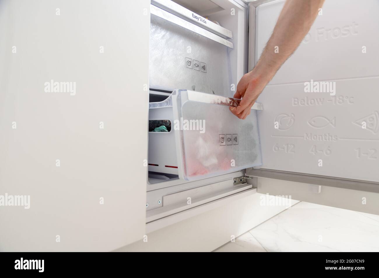 Verschiedene gefrorene Beeren in Plastiktüten im Kühlschrank. Lagerung von Lebensmitteln. Tiefkühlkost. Handöffnende Gefriertruhe. Kunststoffverpackung. Stockfoto