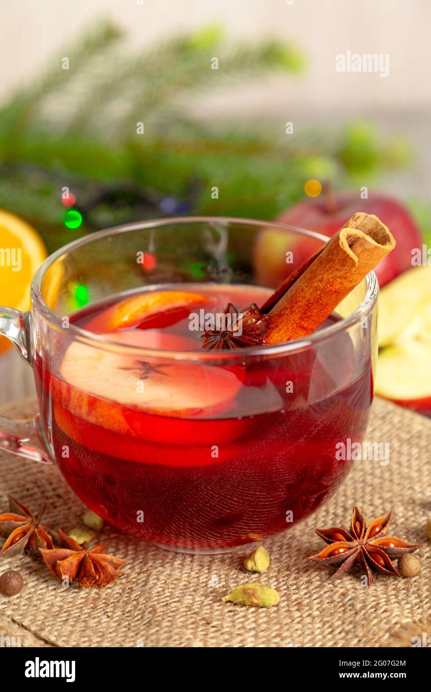 Glühwein mit Gewürzen und Früchten auf einem Holztisch. Heißer Weihnachtsdrink mit Rotwein, Äpfeln, Orangen und Zimt. Traditionelle Feiertagskarte. Stockfoto