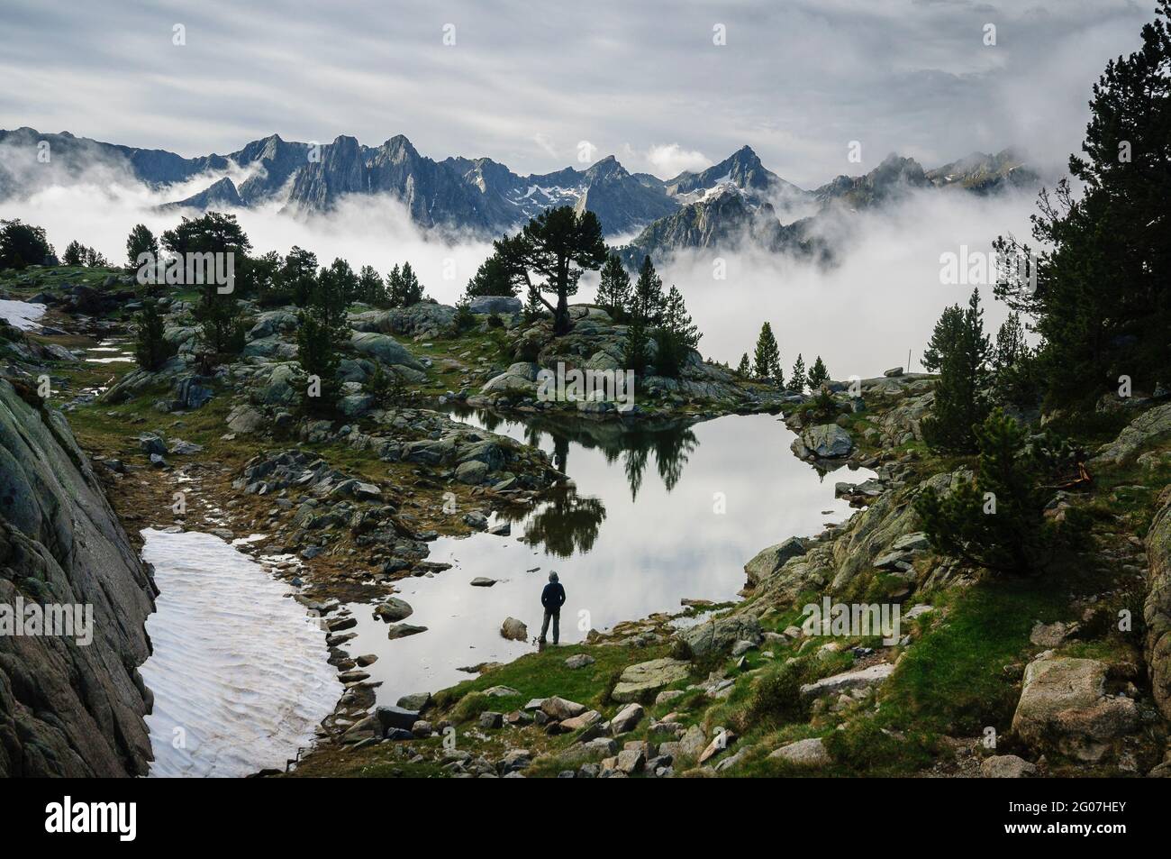 Gipfel des Aigüestortes-Nationalparks, in den Pyrenäen, im Sommer nebliger Sonnenaufgang, von einem See in der Nähe der Amitges-Hütte aus gesehen (Pallars Sobirà, Cataluña) Stockfoto