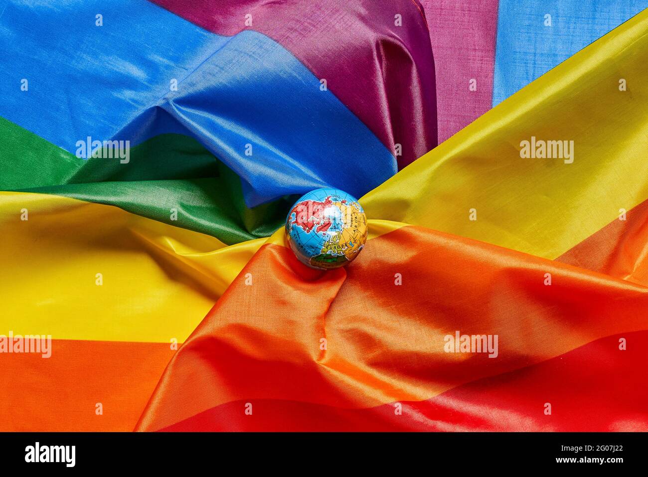 Ein kleiner Globus auf LGBT-Flagge Hintergrund Stockfoto