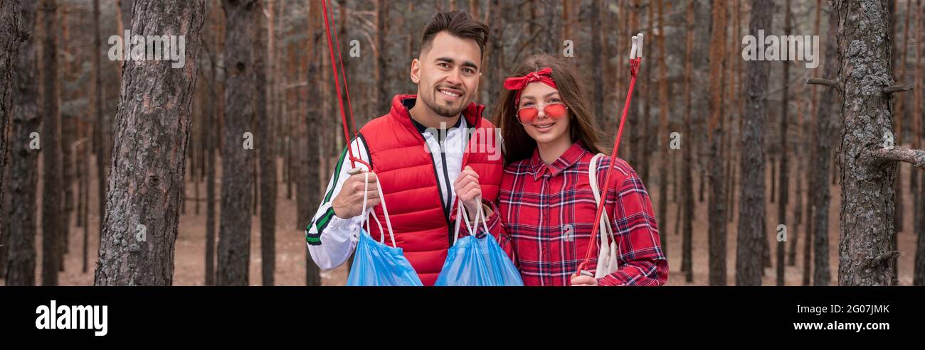 Glückliches Paar mit Müllsäcken, die Pick-up-Werkzeuge im Wald halten, Banner Stockfoto