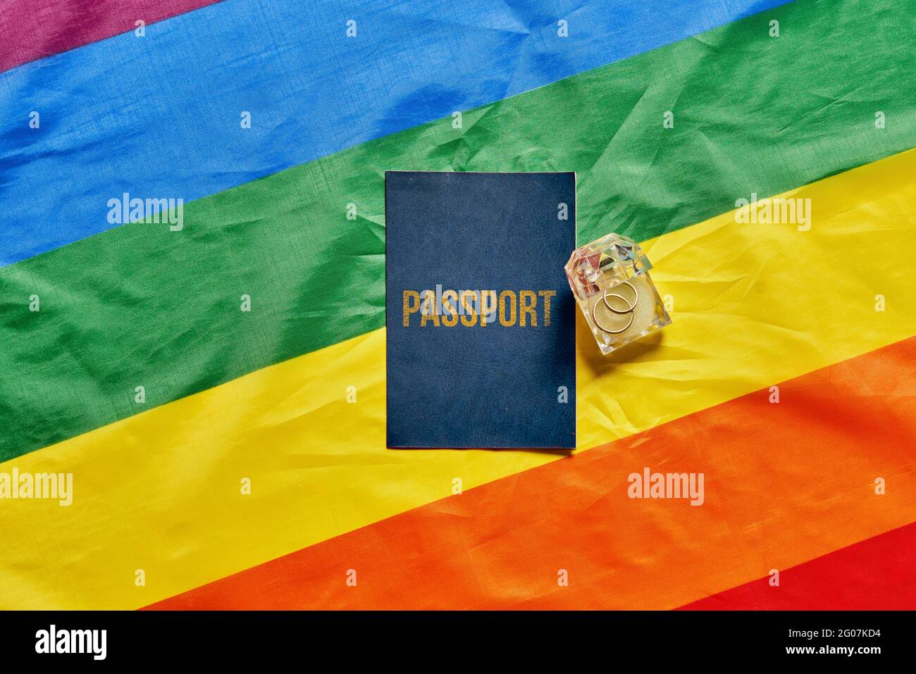 Ein Pass und klingelt auf LGBT-Flagge Hintergrund. LGBT-Hochzeitskonzept. Stockfoto