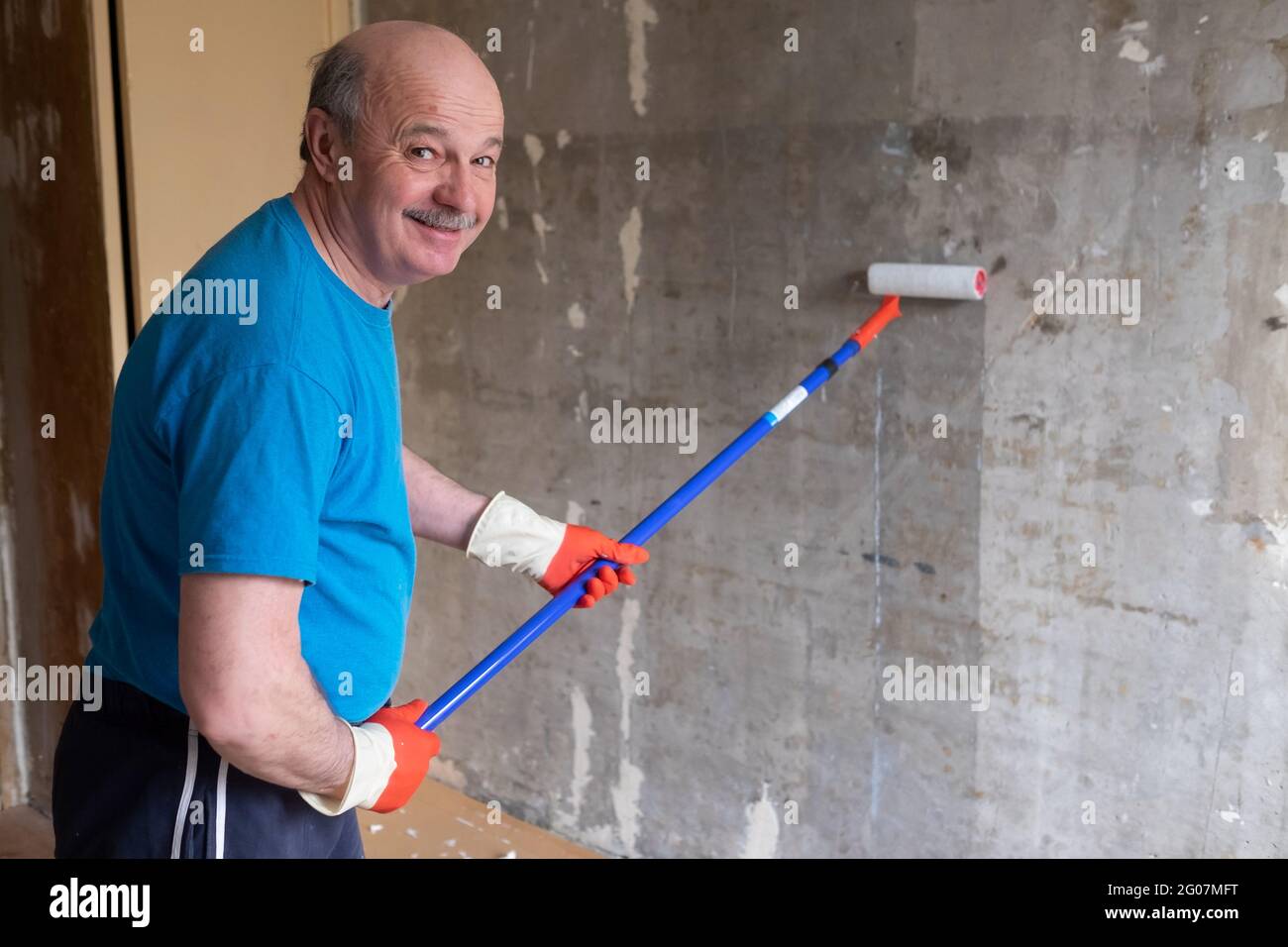 Man malt Zementwände mit Walzenbürste und Grundierung, was eine Renovierung macht. Stockfoto