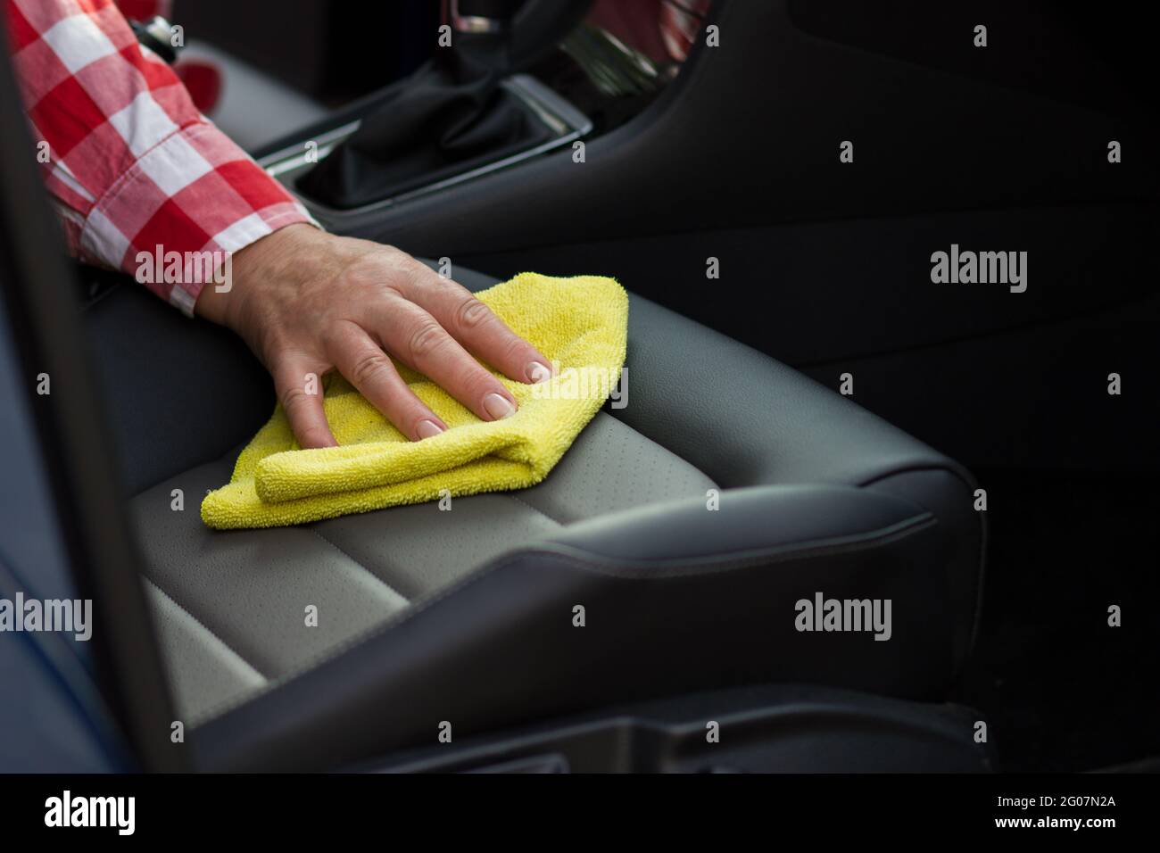 Ältere Frau Reinigung Ledersitz des Autos mit weichen gelben Mikrofaser Tuch. Stockfoto