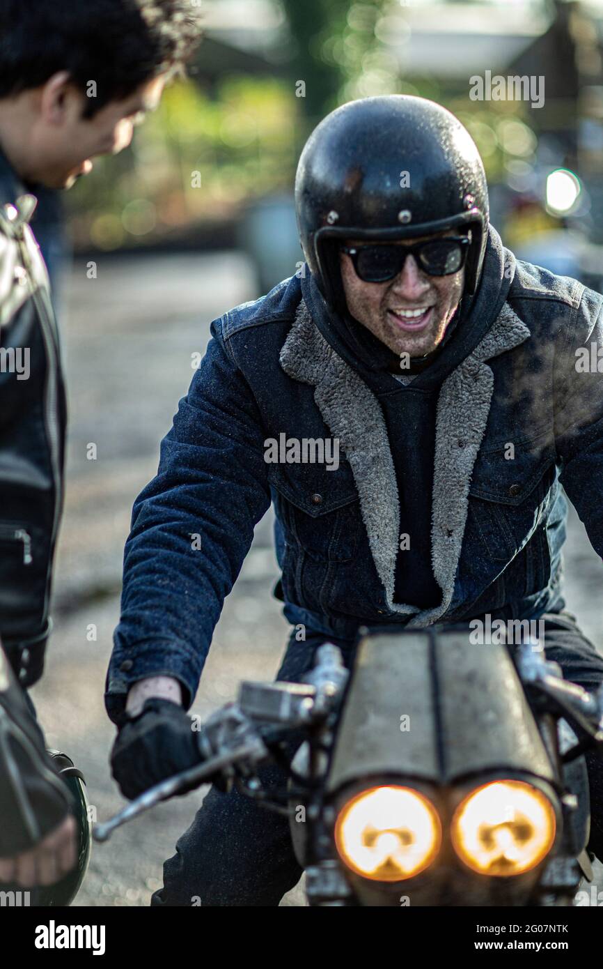 Junger gutaussehender lächelnder Biker, der sich auf die Fahrt vorbereitet. Stockfoto