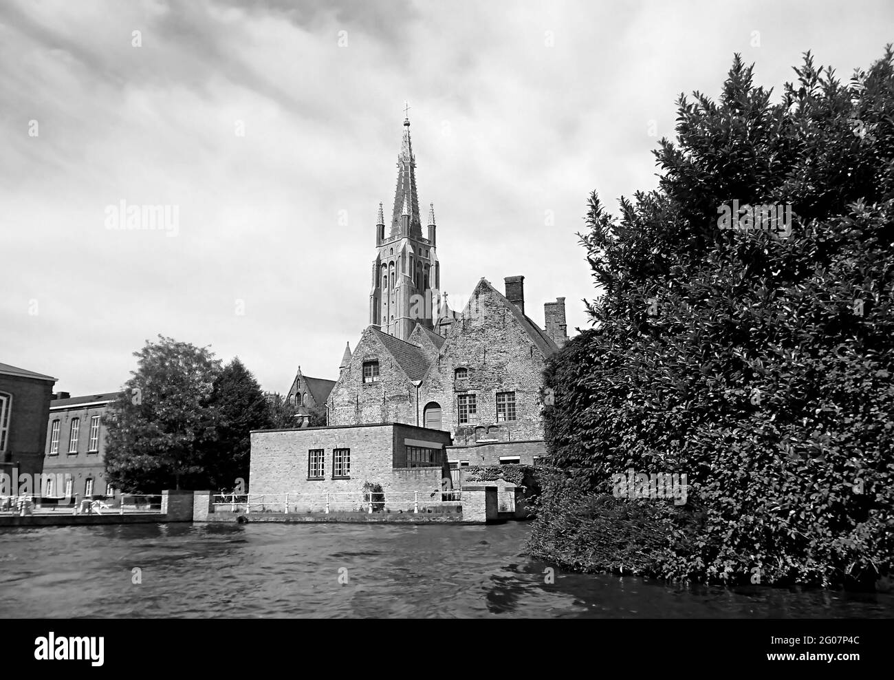 Monochromes Bild der Kanalfahrt im historischen Zentrum von Brügge mit der Kirche unserer Lieben Frau im Hintergrund, Belgien Stockfoto