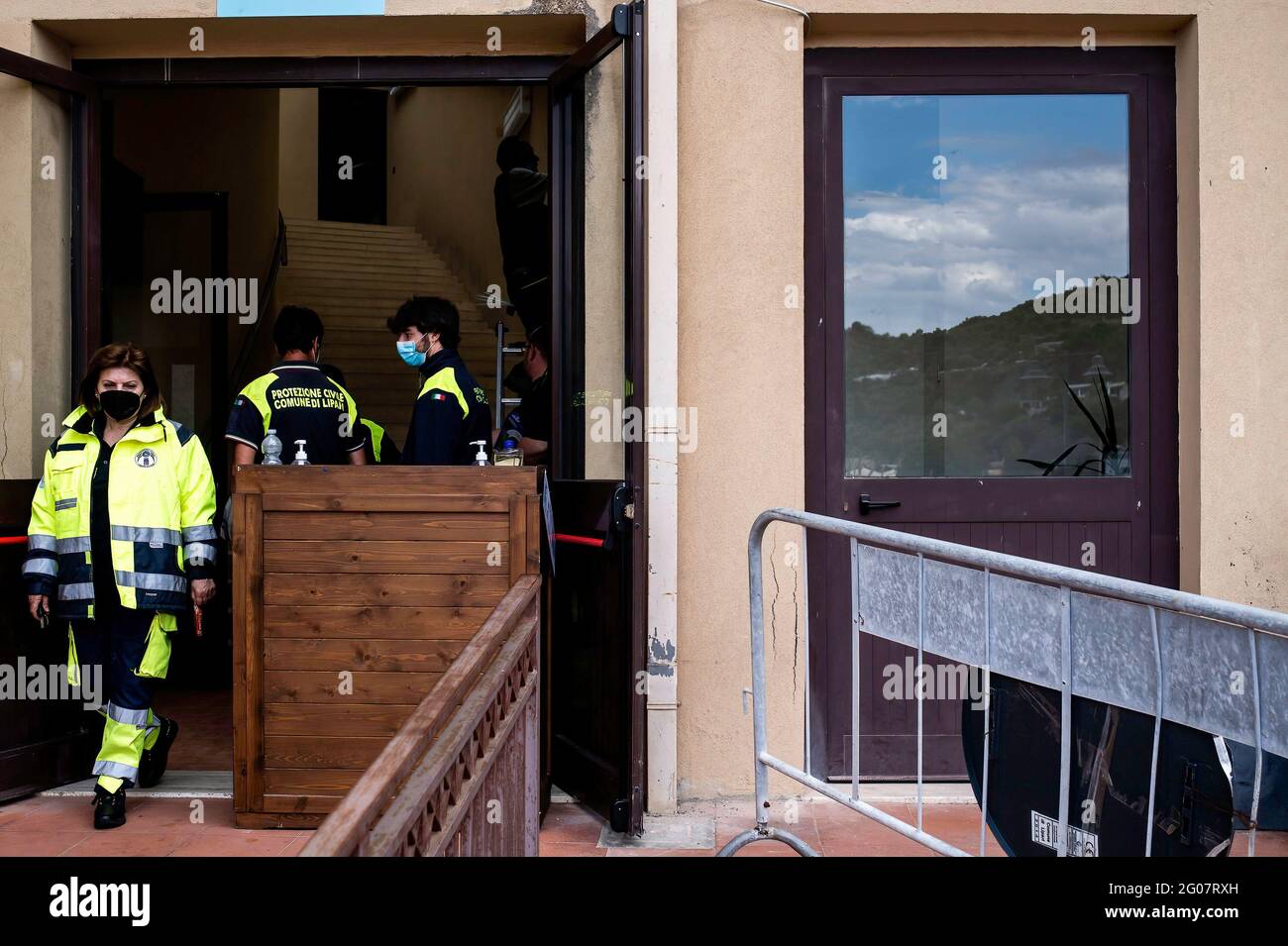 Lipari, Sizilien, Italien. Mai 2021. Menschen des lokalen Katastrophenschutzes am Eingang des Impfzentrums in Lipari gesehen.Laut dem Programm "Covid-freie Inseln" für den Sommer erhielt die Lipari-Bevölkerung, die größte der Äolischen Inseln Siziliens, den Anti-COVID-19-Impfstoff im Kongresszentrum (Palazzo dei Congressi). Das Programm wurde von einem Team der sizilianischen Region unter der Leitung des Sonderbeauftragten für den Notfall in der Region Covid-19 für den Großraum Messina (Ufficio Commissario Ad Acta per l'Emergenza Covid-19 per l'Area Metropolita) durchgeführt Stockfoto