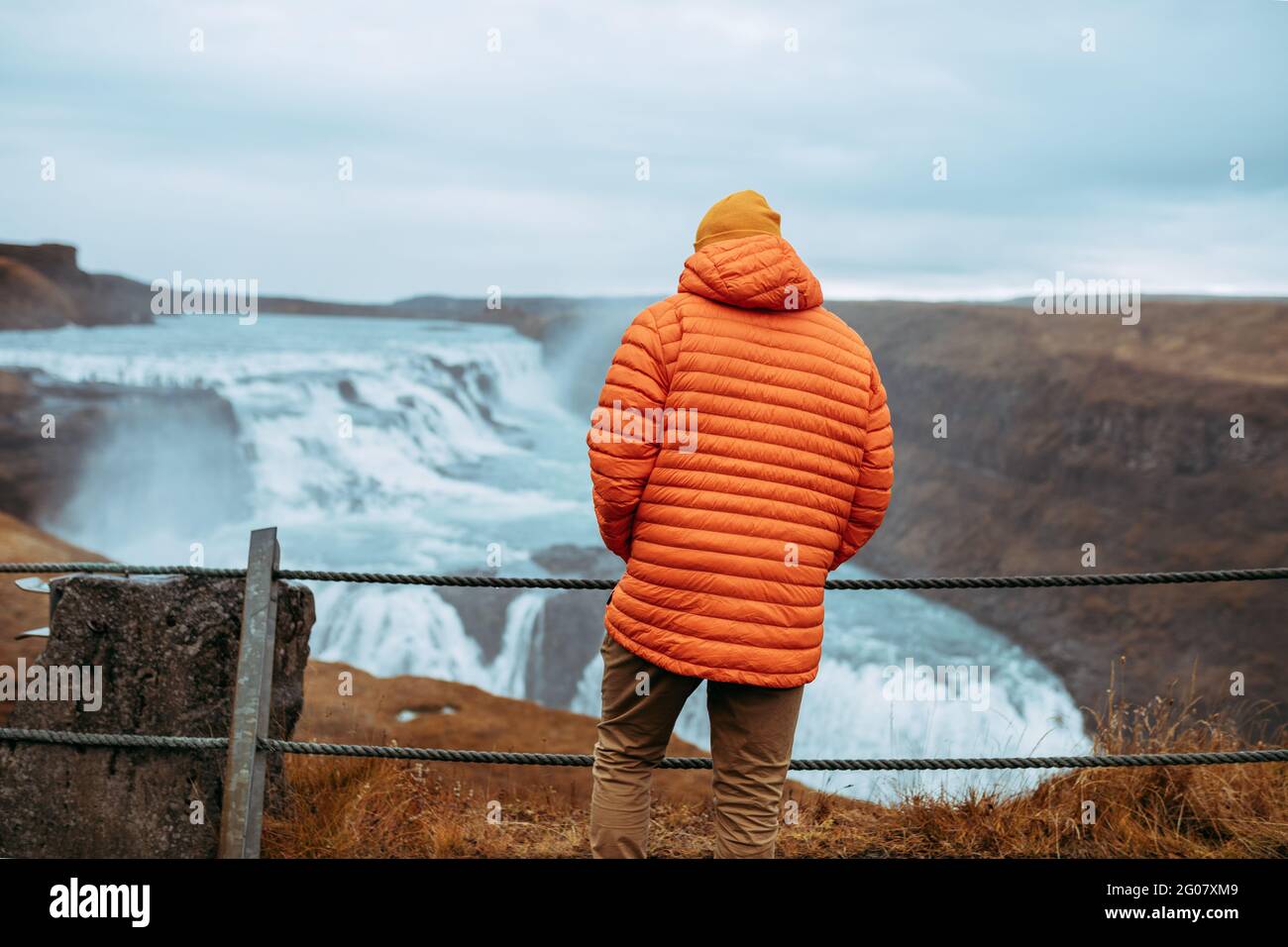 Rückansicht von jungen Touristen im Winter tragen Blick auf Kaskade und Gebirgsfluss zwischen Steinhügel Stockfoto