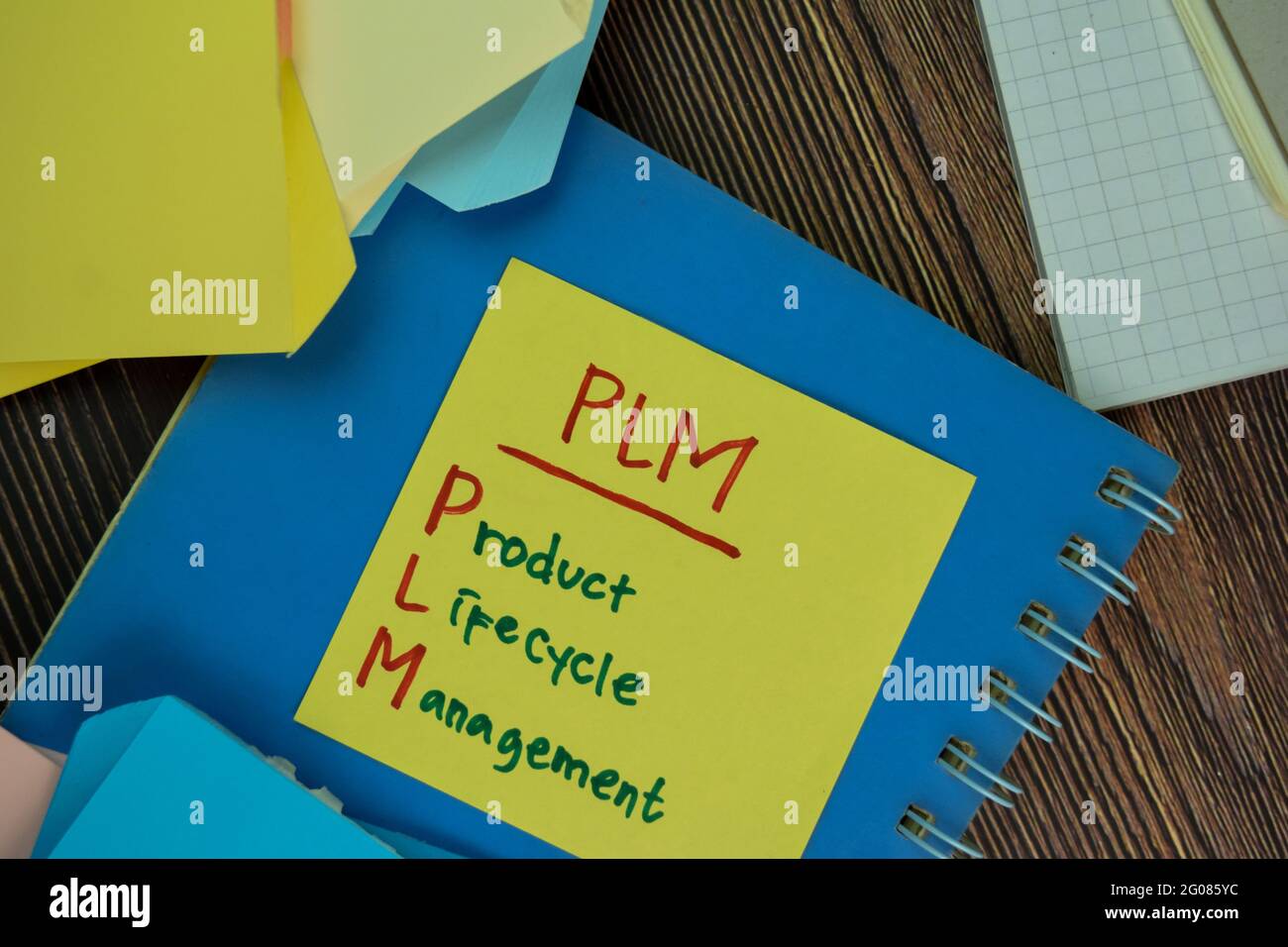 PLM - Product Lifecycle Management Schreiben Sie auf Haftnotizen isoliert auf Holztisch. Stockfoto